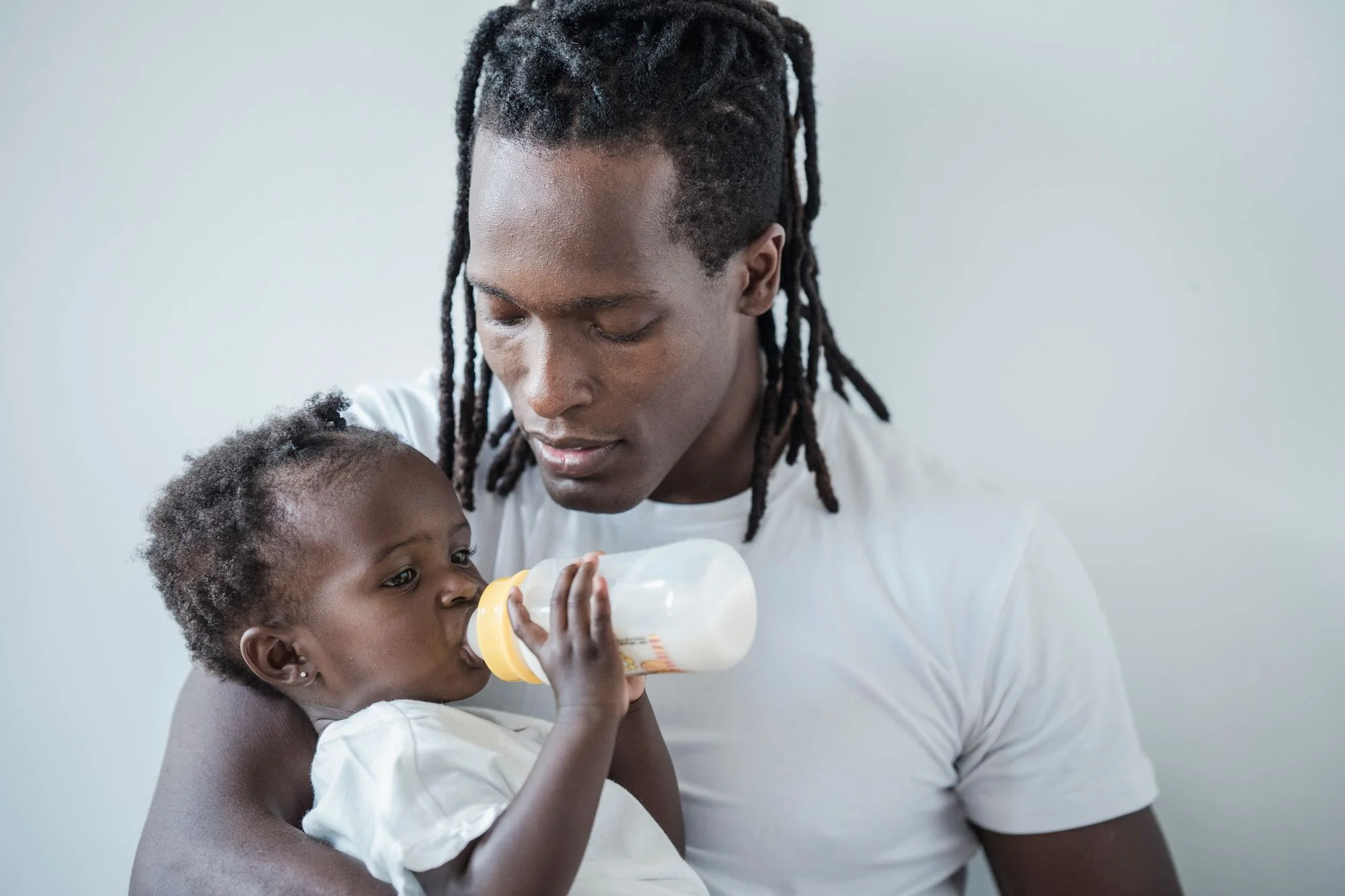Un adulte donne un biberon au bébé : penser aux gestes du quotidien avant de comparer le matériel.